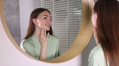 Güzel bir kadın aynada kendine bakıyor.