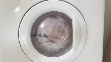 Çamaşır makinesini açtı, farklı giysiler içinde, kapalı.