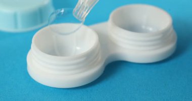 Açık mavi arkaplan üzerine kontak lens takan kadın, yakın plan