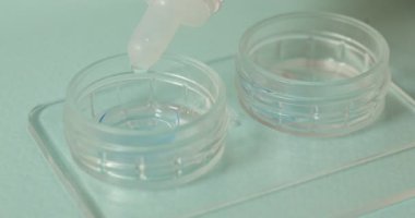 Işık arkaplanındaki kontakt lenslerle birlikte çözelti dosyaya damlıyor, yakın plan