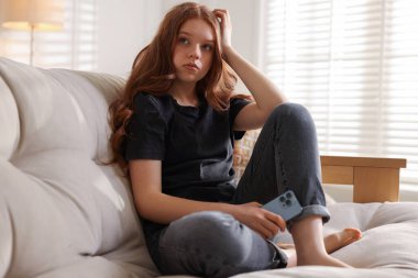 Evdeki kanepede oturan üzgün genç kız.