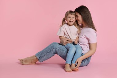 Mutlu anne ve tatlı kızı pembe arka planda
