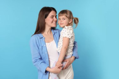 Mutlu anne ve kızı açık mavi arka planda.
