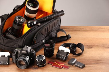 Profesyonel fotoğrafçının ekipmanı ve sırt çantası ahşap masada.