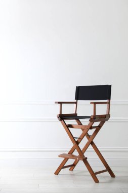 Beyaz duvarın yanında boş bir yönetmen koltuğu, mesaj için boşluk.