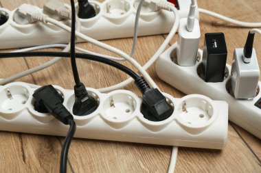 Uzatma güç panoları ahşap zemindeki tıkaçlarla aşırı yüklenmiş, yakın plan.