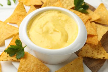 Peynir sosunu kaseye daldırmak ve cipsi masaya koymak, yakın plan.