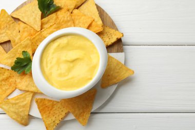 Lezzetli bir peynir sosu ve beyaz ahşap masada nacho cipsi. Metin için boşluk