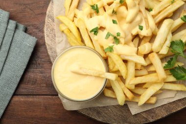 Tabakta leziz peynir sosu, patates kızartması ve ahşap masada maydanoz.