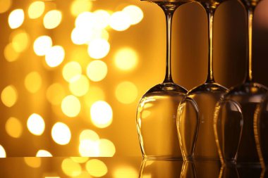 Bulanık ışıklara karşı cam ayna yüzeyinde birçok temiz bardak, yakın plan. Bokeh etkisi