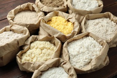 Tahta masadaki kağıt torbalarda farklı türde un, yakın plan.