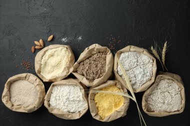 Siyah masa üzerinde, kağıt torbalarda farklı tipte un, düz yerde.