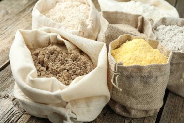 Tahta masadaki poşetlerdeki farklı un türleri, yakın plan.