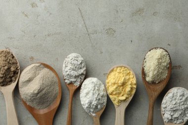 Açık gri masadaki kaşıklarda farklı türde un, düz. Metin için boşluk