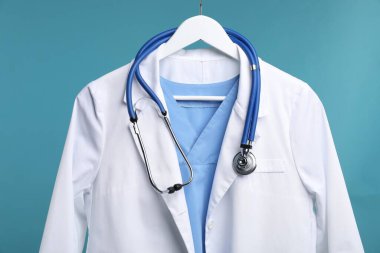 Doktor ceketi ve steteskop mavi arka planda, yakın plan.