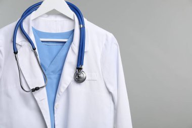 Gri arkaplandaki askıda steteskop olan doktorun ceketi. Metin için boşluk