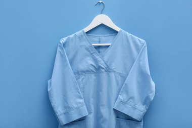 Mavi arka planda askıda çalışan sağlık çalışanı üniforması