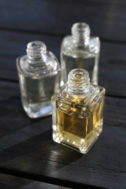 Siyah ahşap arka planda aromatik yağlı parfüm şişeleri, yakın plan.