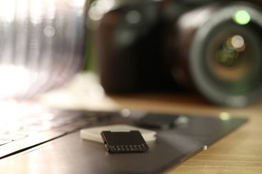 SD hafıza kartları, tutucu, dizüstü bilgisayar ve fotoğraf makinesi ahşap masada, yakın plan.