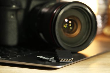 SD hafıza kartları, dizüstü bilgisayar ve fotoğraf makinesi ahşap masada, yakın plan.