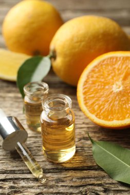 Aromatik esanslı parfüm şişelerini aç. Pipet, portakal ve yapraklar ahşap masada. Yakın plan.