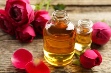 Ahşap masanın üzerinde aromatik esanslı yağlar ve güller olan parfüm şişelerini aç.