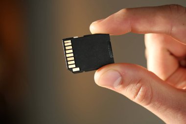 Bulanık arkaplanda SD hafıza kartı olan adam, yakın plan