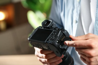 Adamın biri fotoğraf makinesine SD bellek kartı yerleştiriyor. Kapalı mekanda, yakın plan. Metin için boşluk
