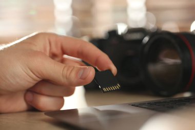 SD bellek kartını bilgisayara yerleştiren adam içerideki masada, yakın plan.