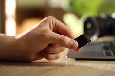 SD hafıza kartı olan bir adam ahşap masada, yakın plan.