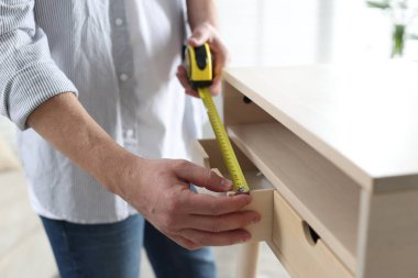 İçerideki bantla ahşap dolabı ölçen adam, yakın plan.