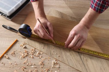 İçerideki bantla ahşap kalası ölçen bir adam.