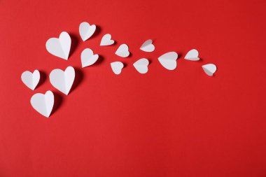 Kırmızı arka planda bir sürü kağıt kalp var. Metin için boşluk