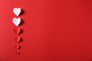 Kırmızı arka planda bir sürü kağıt kalp var. Metin için boşluk