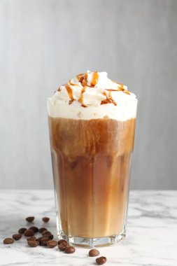 Krem şantili buzlu kahve, şurup ve beyaz mermer masada fasulye.