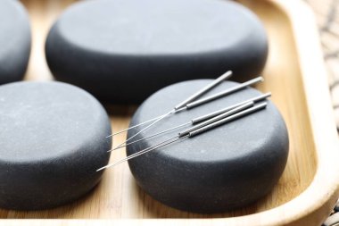 Akupunktur iğneleri ve spa taşları masada, yakın plan.