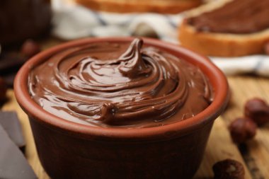 Lezzetli çikolatalı fındık ezmesi ve fındıklar ahşap masada, yakın plan.