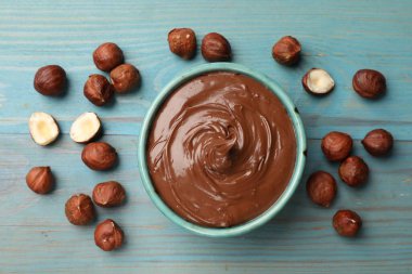 Lezzetli çikolatalı fındık ezmesi ve fındıklar mavi ahşap masada, düz yatıyordu.