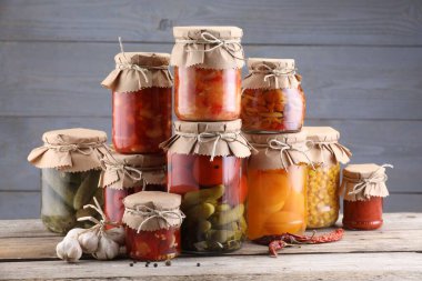 Ahşap masada farklı turşu ürünleri olan bir sürü kavanoz.