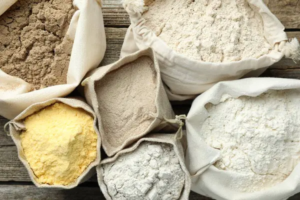 Tahta masada, düz bir zeminde, çuvalda farklı türde un bulunur.