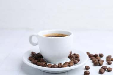 Aromatik kahve fincanda ve fasulye beyaz masada, yakın plan.