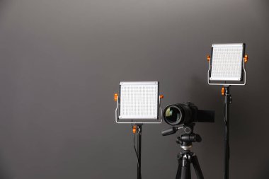 Profesyonel ışıklandırma ekipmanı ve gri arka planda kamera. Metin için boşluk
