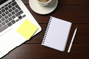 Not defteri, yapışkan not, kalem, kahve ve dizüstü bilgisayar ahşap masada, düz uzanıyordu.