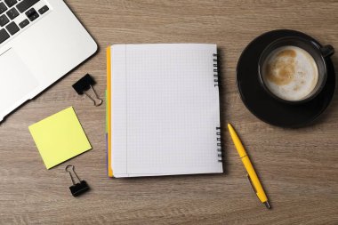 Not defteri, yapışkan not, kalem, cilt klipsleri, ahşap masaya kahve ve dizüstü bilgisayar.