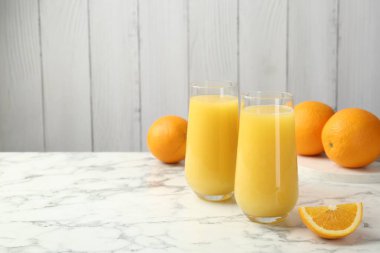 Bardakta portakal suyu ve beyaz mermer masada taze meyve, metin için yer.