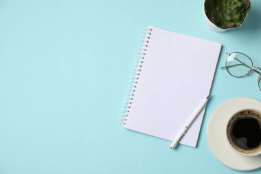 Not defteri, kalem, bardaklar, kahve ve açık mavi arka planda çiçek dekoru. Metin için boşluk