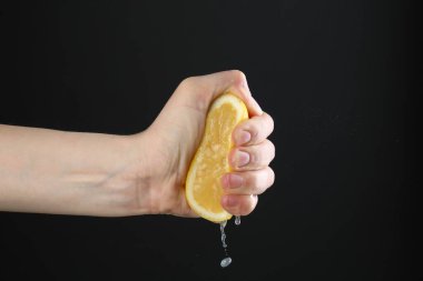 Siyah arka planda limon sıkan kadın, yakın plan.