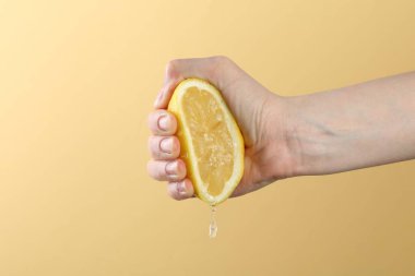 Sarı arka planda limon sıkan kadın, yakın plan.