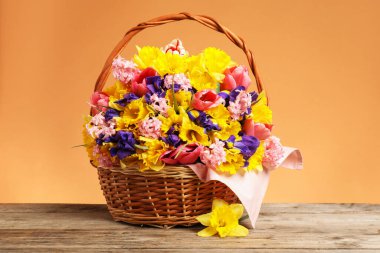 Tahta masanın üzerinde mercan zemin üzerinde güzel çiçekler olan sepet, yakın plan.