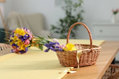 İçerideki masada güzel çiçekler olan hasır sepet.